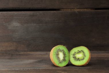 Koyu ahşap arka planda iki parça olgun kivi. Kopyalama alanı olan pankart