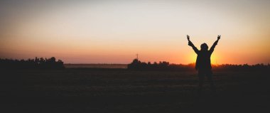 Batan güneşe karşı bir kızın silueti. Akşamları buğday tarlasında genç bir kadın.