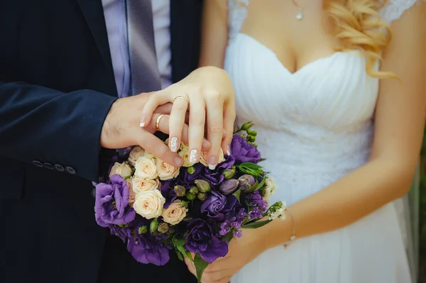 Novia y novio tomados de la mano en un ramo . — Foto de Stock