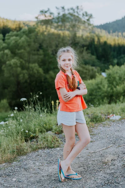 Op een zonnige dag wandelt een portret van een mooi jong toeristisch meisje, met een rugzak, modevrouw, door het bos, de achtergrond van bomen. Onderwerp: recreatie, mooi uitzicht, sport, reizen. — Stockfoto