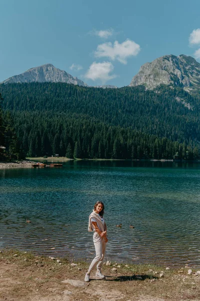 女孩期待的湖 森林和山脉在黑山都拉斯国家公园 观光旅游的姑娘欣赏着美丽的湖景 针叶林和迷人的风景 坐在高山绿松石湖畔的大石头上 远足I — 图库照片