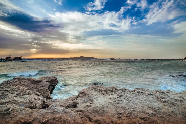 Wonderful solar Red Sea beach at a luxury hotel, at sunset. Sharm El Sheikh, Sinai, Egypt. Gold sunset with mountains and big wave. — Stock Photo, Image