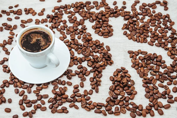 Tasse Kaffee und Bohnen auf beigem Hintergrund mit menschlichen — Stockfoto