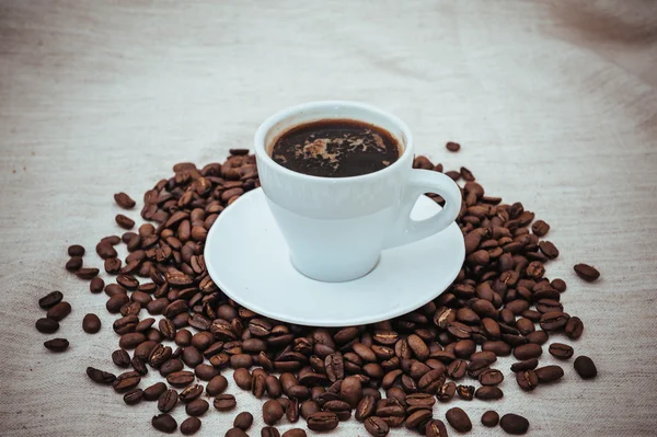 Tasse Kaffee und geröstete Bohnen auf beigem Hintergrund — Stockfoto