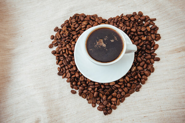 Cup of Coffee and roasted beans in heart shape isolated on white background.