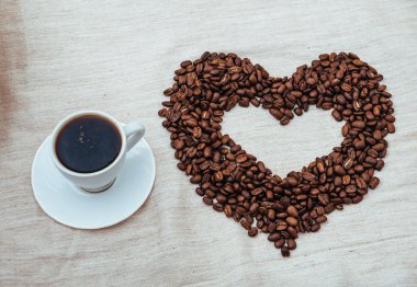 Bir fincan kahve. kavrulmuş fasulye kalp şeklinde. Beyaz arka plan üzerinde izole.