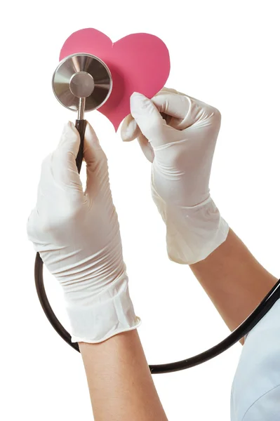 Positive female doctor standing with stethoscope and red heart symbol isolated on white background — Stock Photo, Image