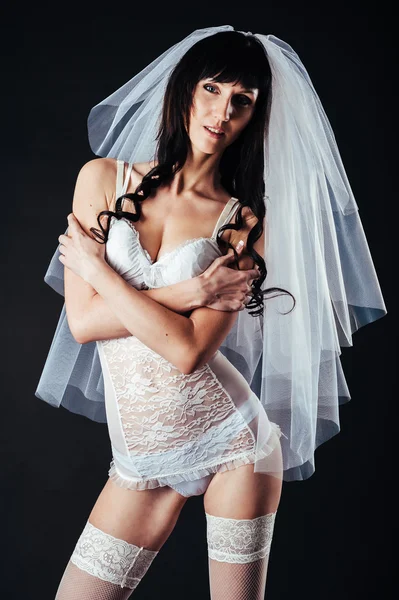 性感美丽的裸体新娘的面纱在黑色背景上的白色情趣内衣。美丽的女人的画像 图库图片