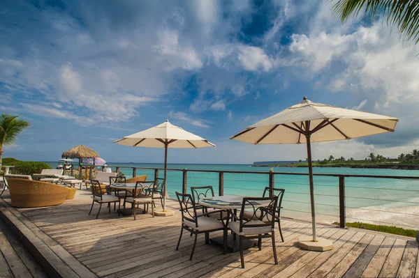 Outdoor restaurant at the seashore. Table setting in tropical Summer Beach Cafe, ocean and sky. Dominican Republic, Seychelles, Caribbean, Bahamas. Relaxing on remote Paradise beach.