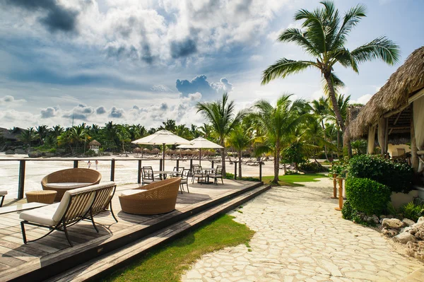 Outdoor restaurant at the seashore. Table setting in tropical Summer Beach Cafe, ocean and sky. Dominican Republic, Seychelles, Caribbean, Bahamas. Relaxing on remote Paradise beach. — Stock Photo, Image