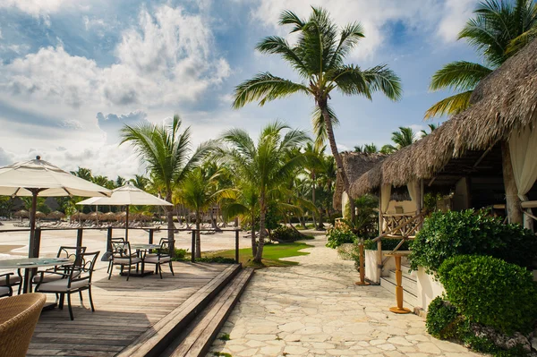 Outdoor restaurant at the seashore. Table setting in tropical Summer Beach Cafe, ocean and sky. Dominican Republic, Seychelles, Caribbean, Bahamas. Relaxing on remote Paradise beach. — Stock Photo, Image