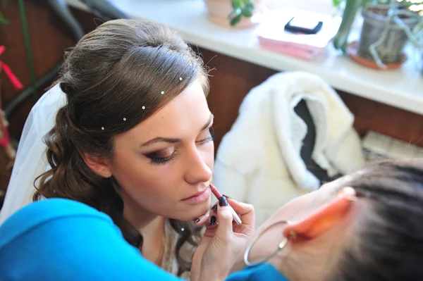 Mulher aplicando maquiagem para a noiva em seu dia de casamento perto do espelho. Fechar a maquilhagem do artista — Fotografia de Stock