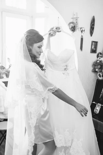 Happy beautiful bride tries on a wedding dress dressing gown. Girl have final preparation for wedding. Beautiful newlywed woman with long hair — Stock Photo, Image