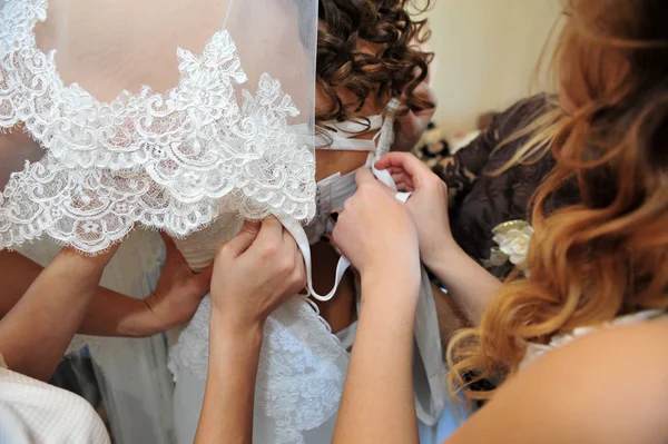 Bridesmaid is helping the bride tying bow on wedding dress. — Stock Photo, Image