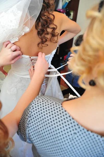 Druhna pomaga młodej wiązanie łuk na suknię ślubną. — Zdjęcie stockowe
