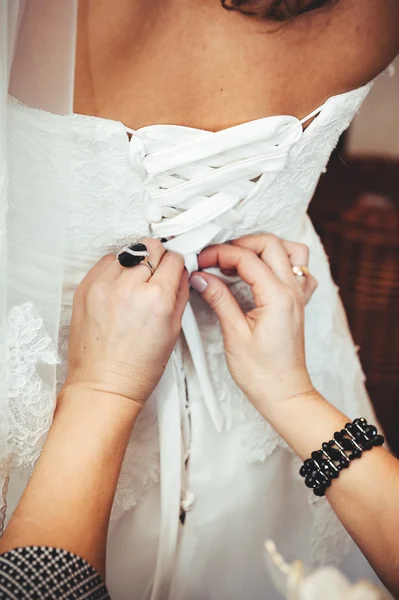 Bridesmaid is helping the bride tying bow on wedding dress. — Stock Photo, Image