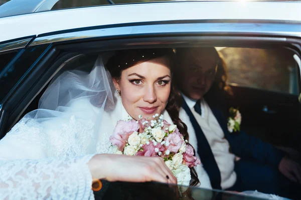 Portret van gelukkige bruid en bruidegom in de auto. — Stockfoto