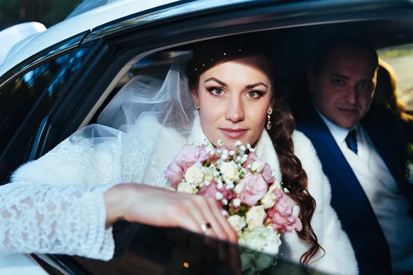 Portret van gelukkige bruid en bruidegom in de auto. — Stockfoto