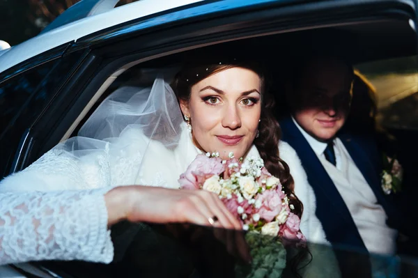 Portret van gelukkige bruid en bruidegom in de auto. — Stockfoto