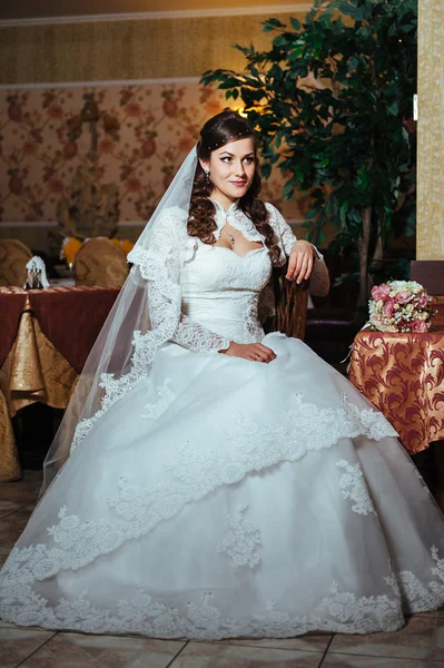 Gorgeous bride blonde in wedding dress on luxury interior with diamond jewelry posing at home and waiting for groom. — Stock Photo, Image