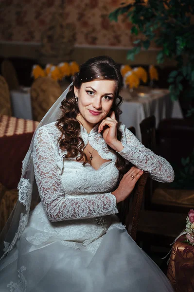 Splendida sposa bionda in abito da sposa su interni di lusso con gioielli di diamanti in posa a casa e in attesa di sposo . — Foto Stock