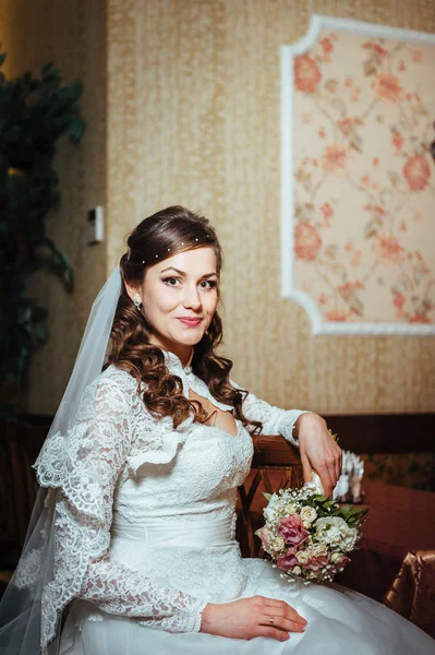 Hinreißende Braut Blondine im Hochzeitskleid auf luxuriösem Interieur mit Diamantschmuck posiert zu Hause und wartet auf Bräutigam. — Stockfoto