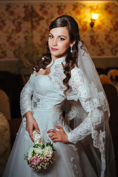 Splendida sposa bionda in abito da sposa su interni di lusso con gioielli di diamanti in posa a casa e in attesa di sposo . — Foto Stock