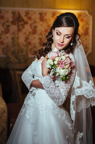 Linda noiva loira em vestido de noiva no interior de luxo com jóias de diamante posando em casa e esperando o noivo . — Fotografia de Stock