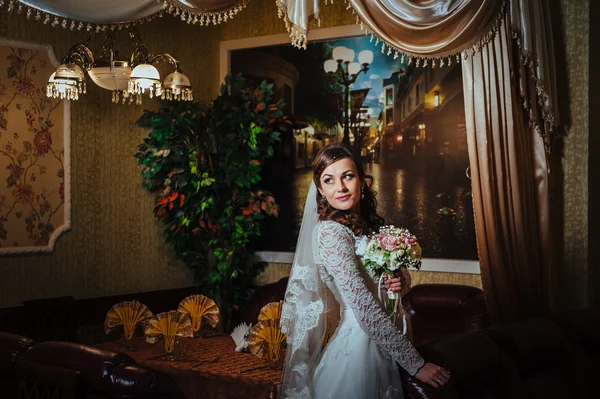 Splendida sposa bionda in abito da sposa su interni di lusso con gioielli di diamanti in posa a casa e in attesa di sposo . — Foto Stock