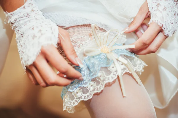 Noiva colocando uma liga de casamento em sua perna — Fotografia de Stock