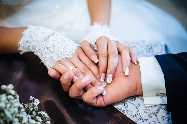 Close up hands of Loving couple sitting in a cafe on their wedding day. Bouquet flowers — Stock Photo, Image