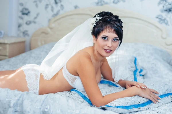 Nahá nevěsta striptýz. Krásná dívka v bílém prádle hrát s její svatební šaty. Veselá dívka pózuje — Stock fotografie