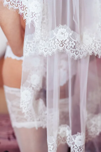 Стриптиз для обнаженной невесты. Красивая девушка в белом белье играть со своим свадебным платьем. Молодая веселая женщина позирует — стоковое фото