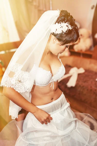 Nahá nevěsta striptýz. Krásná dívka v bílém prádle hrát s její svatební šaty. Veselá dívka pózuje — Stock fotografie