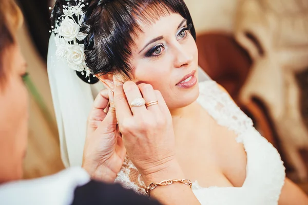 Bruid bedrijf oorbellen. Portret van een prachtige vrouw haar earring aanpassen. Voorbereiding moment voor de bruiloft. — Stockfoto