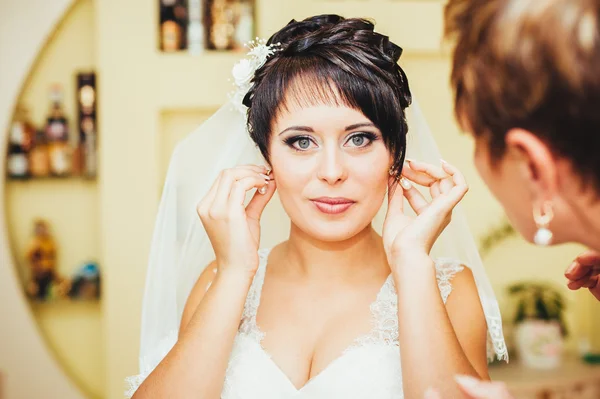 Braut mit Ohrringen. Porträt einer hinreißenden Frau, die ihren Ohrring justiert. Moment der Vorbereitung auf die Hochzeit. — Stockfoto