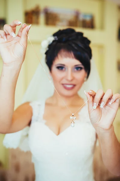 Sposa con orecchini in mano. Ritratto di una donna stupenda che si aggiusta l'orecchino. Momento di preparazione per il matrimonio . — Foto Stock