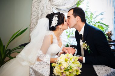 Sevgi dolu çift düğün gününde bir kafede oturuyor. Buket çiçek