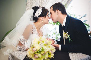 Sevgi dolu çift düğün gününde bir kafede oturuyor. Buket çiçek