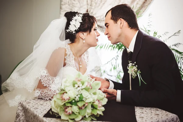 Loving couple sitting in a cafe on their wedding day. Bouquet of flowers — Stock Photo, Image