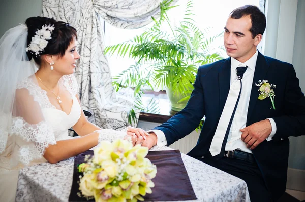 Coppia amorevole seduta in un caffè il giorno del loro matrimonio. Bouquet di fiori — Foto Stock