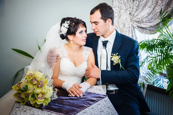 Coppia amorevole seduta in un caffè il giorno del loro matrimonio. Bouquet di fiori — Foto Stock