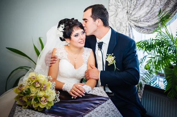 Loving couple sitting in a cafe on their wedding day. Bouquet of flowers — Stock Photo, Image