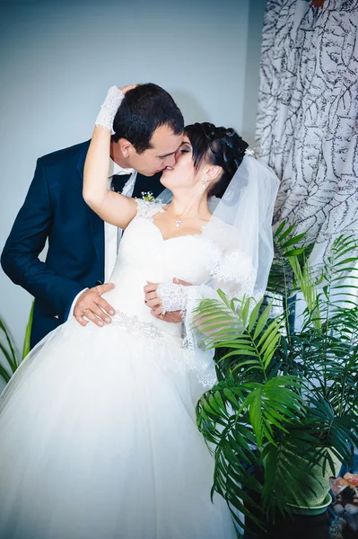 Affascinante sposa con sposo abbraccia e baci sulla loro celebrazione di nozze in lussuoso ristorante. bouquet di fiori, abito da sposa. coppia appena sposata atluxury moderna sala d'albergo — Foto Stock