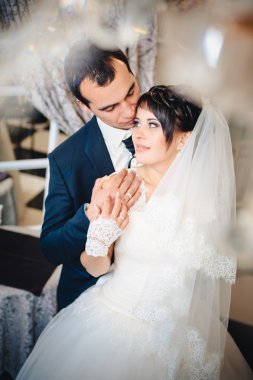 Büyüleyici gelinle damat kucaklayan, onların düğün kutlama lüks restoranda öper. buket çiçek, gelinliğin. Yeni evli çift atluxury modern otel binası