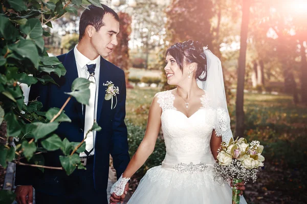 Young couple kissing in wedding gown. Bride holding bouquet of flowers — Stock Photo, Image