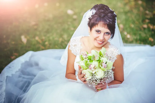 Portrait de belle jeune mariée tenant un bouquet lumineux dans les mains. célébration de mariage. nature fond vert. femme seule à l'extérieur au parc — Photo