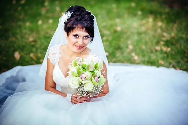 Retrato de hermosa novia joven sosteniendo ramo brillante en las manos. celebración de la boda. naturaleza fondo verde. mujer sola al aire libre en el parque — Foto de Stock