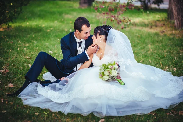 Νεαρό ζευγάρι που φιλιούνται στο νυφικό. νύφη εκμετάλλευση μπουκέτο λουλούδια — Φωτογραφία Αρχείου