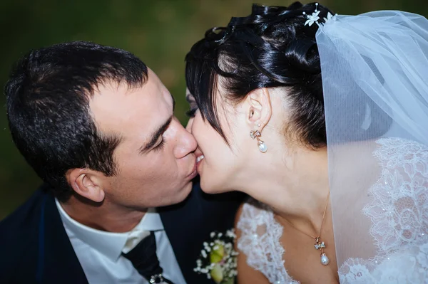 Gelinlik içinde öpüşme genç bir çift. Gelin holding buket çiçek — Stok fotoğraf